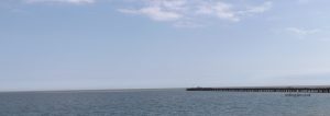 A pier stretching out into the sea on a bright clear day