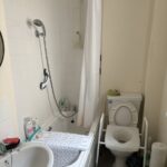 A small bathroom with bath, bath board across it and toilet with mowbray toilet frame visible